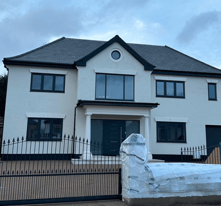 New build house with grey tiled roof and iron gates