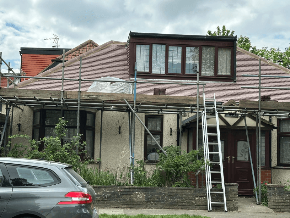 Roof replacement in progress with scaffolding on detached house